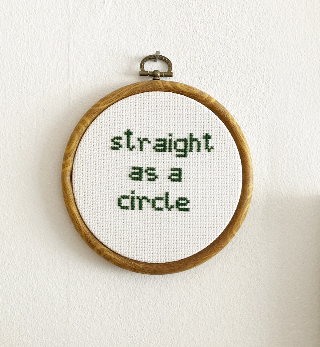 Foto von einem kreisrunden gestickten Bild mit dem Text "Straight like a Circle".